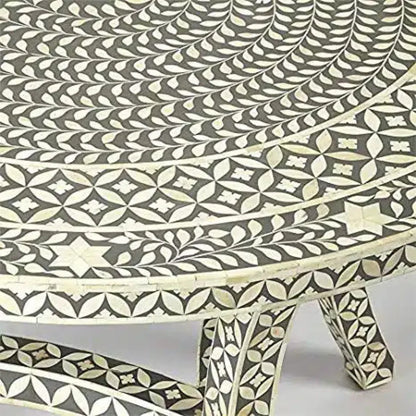Close-up of ivory bone inlay leaves, flowers, and geometric borders on the gray dining tabletop and edge.