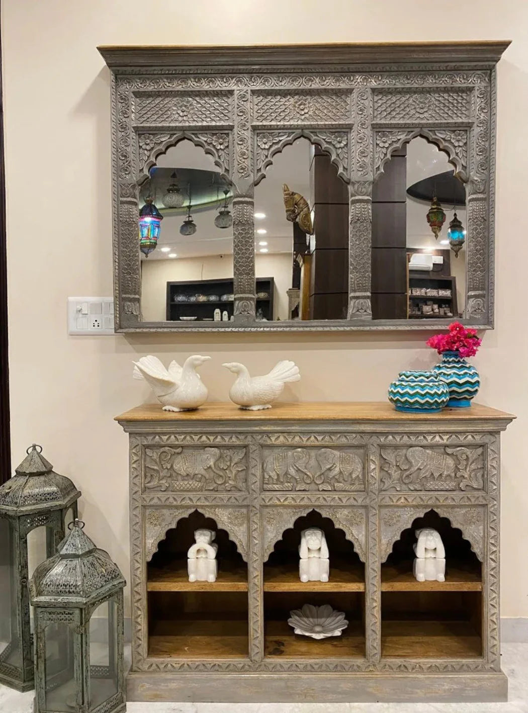 Gray carved wooden jharokha wall mirror with three scalloped arches and floral detailing, displayed above a matching console.