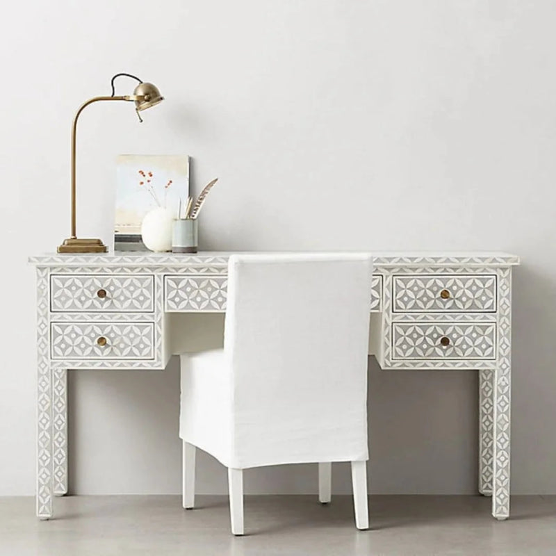 Grey geometric bone inlay study desk with 5 drawers, intricate diamond inlay across body and legs, brass circular knobs, styled with a white chair and gold task lamp in a minimal room
