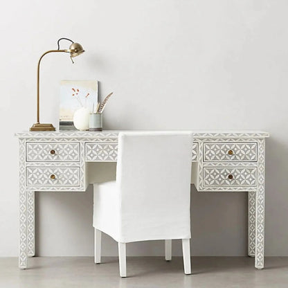 Grey geometric bone inlay study desk with 5 drawers, intricate diamond inlay across body and legs, brass circular knobs, styled with a white chair and gold task lamp in a minimal room