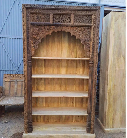 Grand dark walnut-finished hand-carved solid wood bookcase featuring an ornate scalloped arch, floral engravings, and five wide open shelves.
