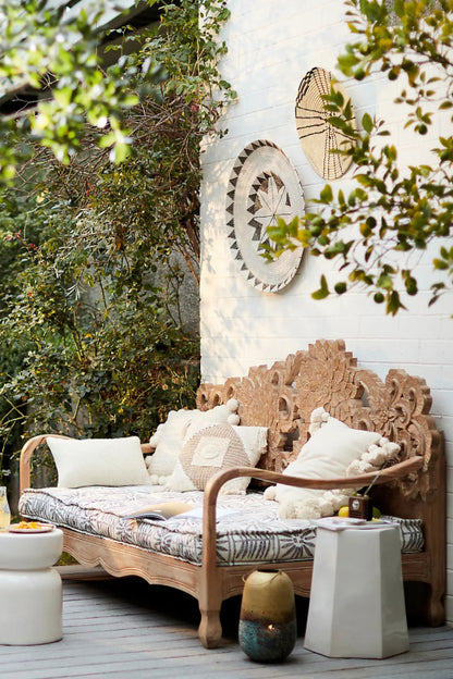 Light-finish wooden daybed with an oversized lotus-inspired carved backrest.
