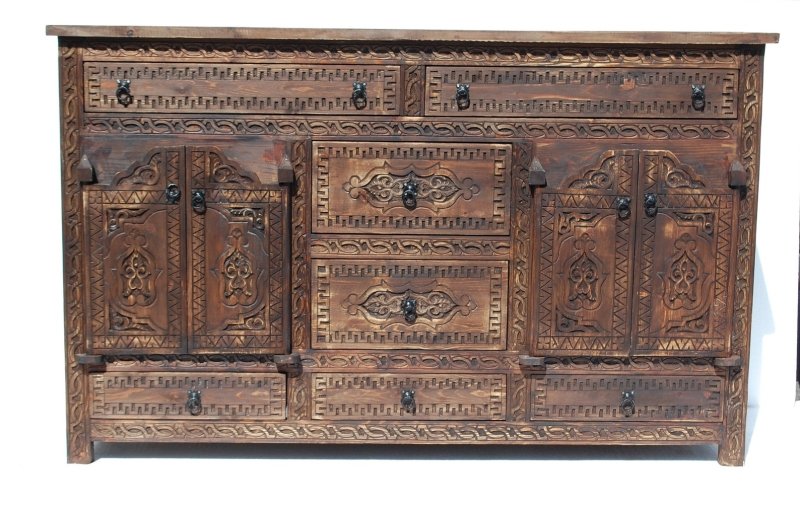 A wide, dark wood  handmade Moorish carved wooden cabinet with multiple drawers and two central doors featuring intricate geometric hand-carved patterns.