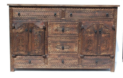 A wide, dark wood  handmade Moorish carved wooden cabinet with multiple drawers and two central doors featuring intricate geometric hand-carved patterns.