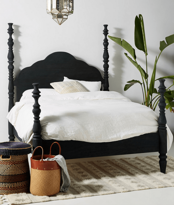 Rosalie hand carved solid wood four-poster bed frame featuring high scalloped headboard and turned posts in a matte ebonized black finish.