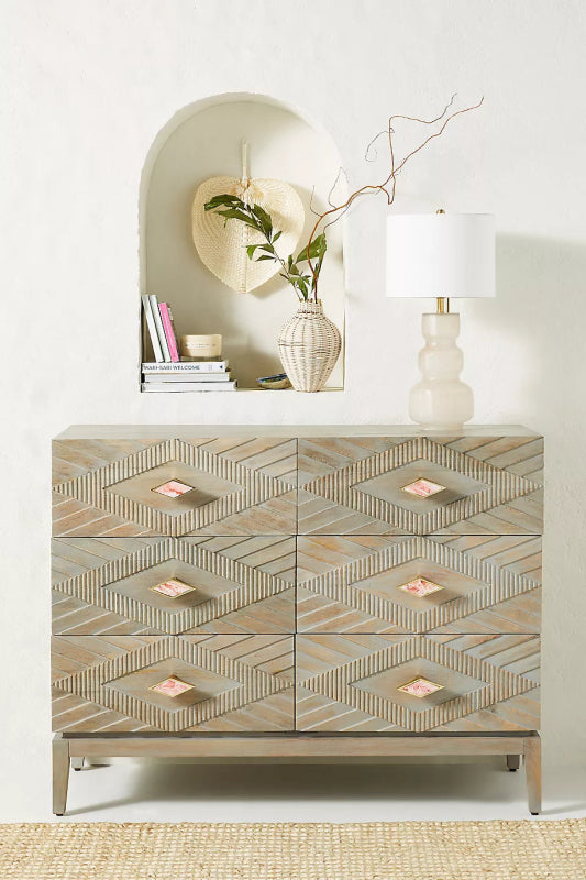 The Samuel 6-drawer solid wood dresser featuring a hand-carved geometric diamond and chevron pattern with a natural weathered finish and tapered legs.