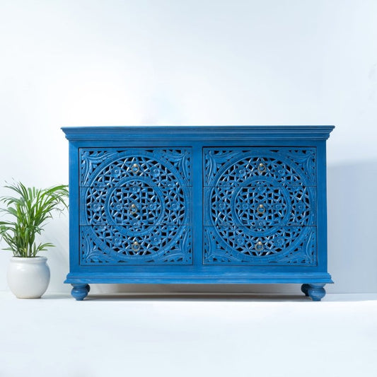 A 6-drawer solid wood dresser in indigo blue featuring intricate hand-carved Moroccan lattice patterns and vintage brass ring pulls against a white background.