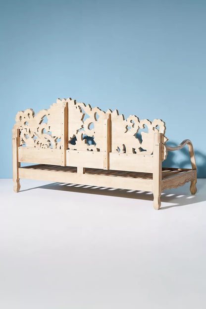 Hand-carved wooden daybed with a broad floral backrest and airy slatted seat.