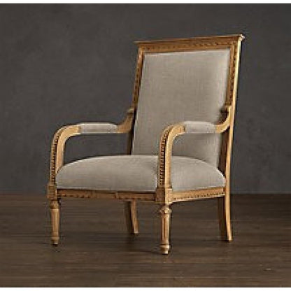A side-angle view of a luxury Louis XVI style bergère chair with a gilded solid wood frame and neutral linen upholstery against a dark backdrop.