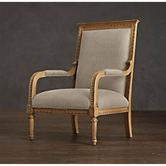 A side-angle view of a luxury Louis XVI style bergère chair with a gilded solid wood frame and neutral linen upholstery against a dark backdrop.