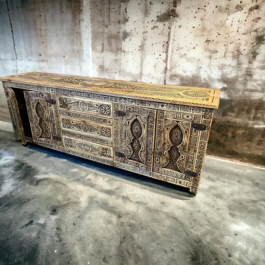 A wide, solid wood handmade African design carved cabinet with honey-toned wood and dark-etched geometric tribal patterns across the drawers, doors, and top.