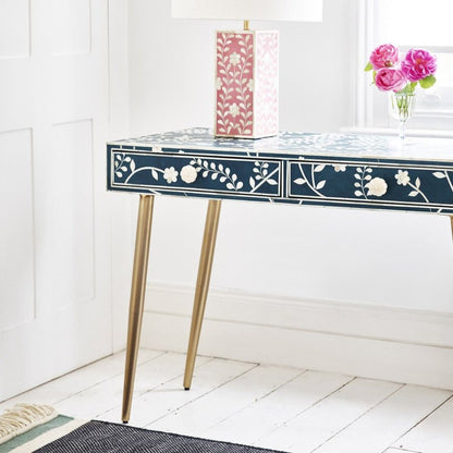 Blue floral bone inlay console desk with white vine and rose pattern on drawers, brass legs, styled with a pink floral table lamp and fresh roses in a white-panelled room