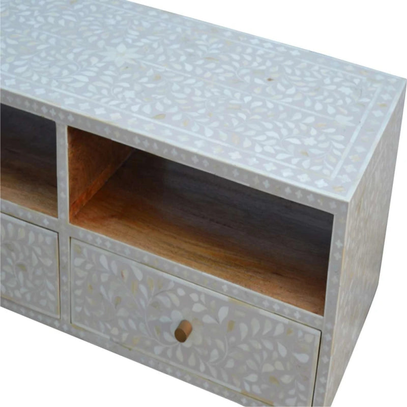 Angled detail of white bone inlay TV cabinet showing open cubby interior, hand-inlaid floral pattern on top panel, and drawer with knob.