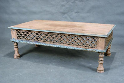 Vintage-style coffee table in natural wood with weathered blue paint accents, featuring an open-work lattice apron and decorative turned legs.