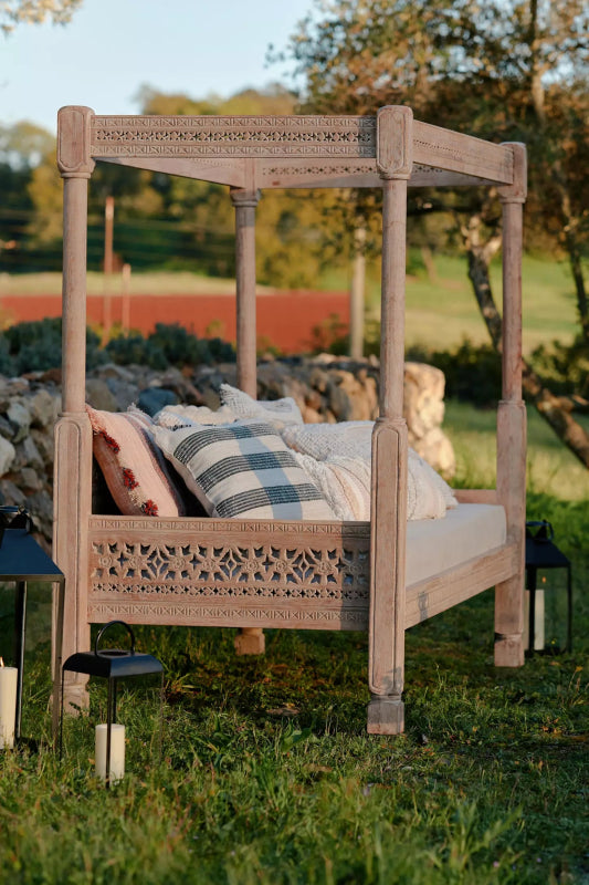 Hand-carved wooden Ezana daybed with a tall canopy frame and intricate lattice-style backrest.