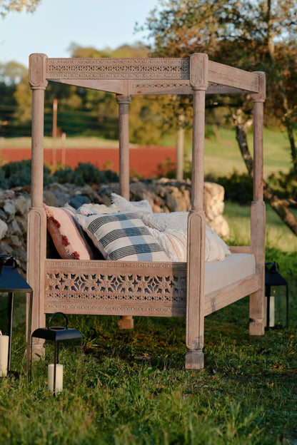 Hand-carved wooden Ezana daybed with a tall canopy frame and intricate lattice-style backrest.