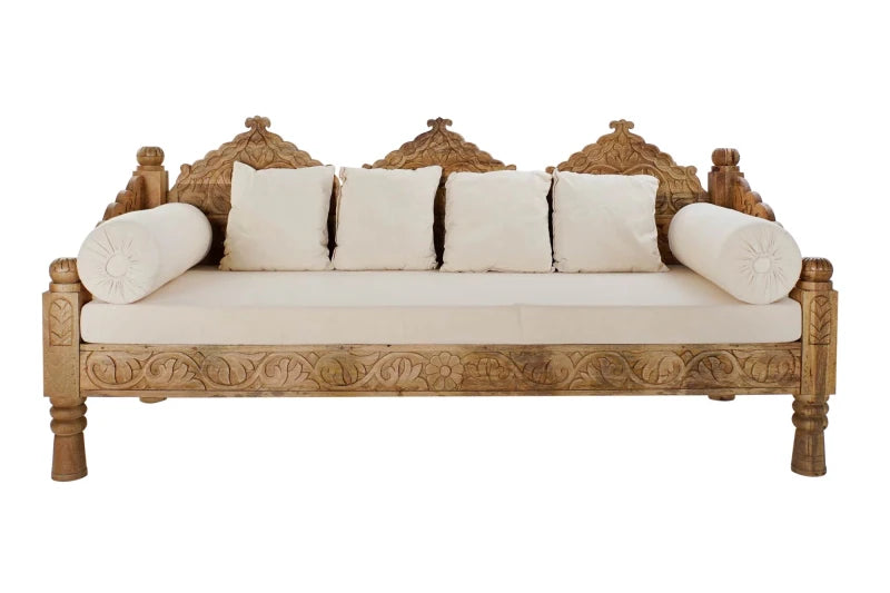 Bohemian style carved light wood daybed sofa with velvet mattress and cylindrical bolster pillows.