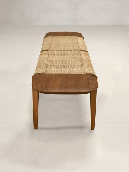 Designer natural wood bench featuring hand-woven cane, a clean silhouette, and sturdy teak construction.