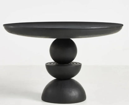 Sculptural modern round dining table in matte black finish featuring a unique totemic pedestal base hand-carved from solid wood.