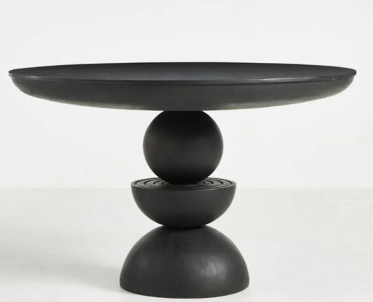 Sculptural modern round dining table in matte black finish featuring a unique totemic pedestal base hand-carved from solid wood.
