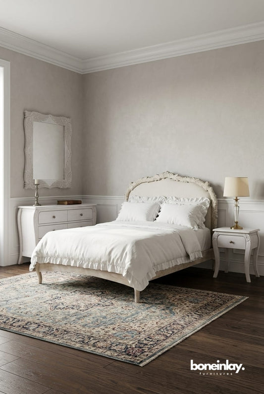 A curated lifestyle setting of the Menagerie bedroom suite, featuring a centerpiece hand-carved bed with an upholstered headboard in a neutral linen fabric. The set is flanked by matching cabriole-leg nightstands against a serene dusty blue wall, styled with a plush ivory rug and a minimalist floral chandelier to evoke a "Quiet Luxury" aesthetic.