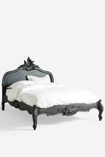 A perspective shot of the Menara bed highlighting the fluid, curved lines of the frame and the handcrafted floral carvings along the side rails and cabriole feet.