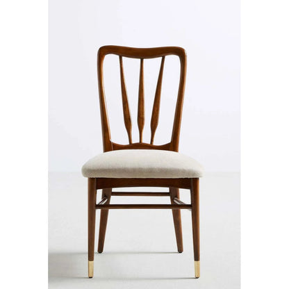 Front view of a mid-century modern solid wood dining chair with a curved spindle back, light beige upholstered seat, and brass-capped tapered legs.
