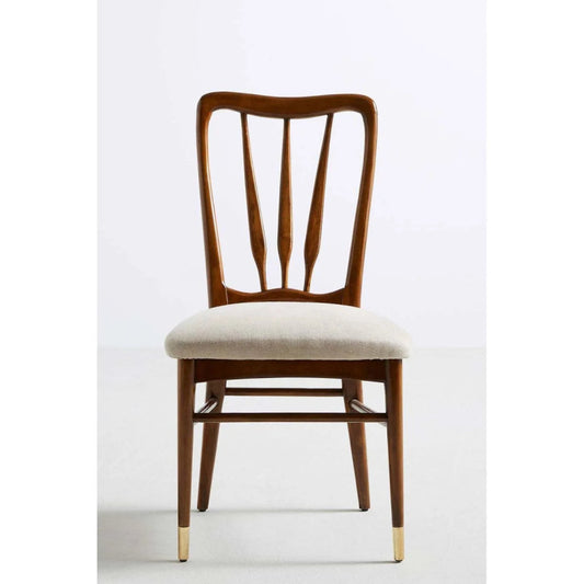 Front view of a mid-century modern solid wood dining chair with a curved spindle back, light beige upholstered seat, and brass-capped tapered legs.