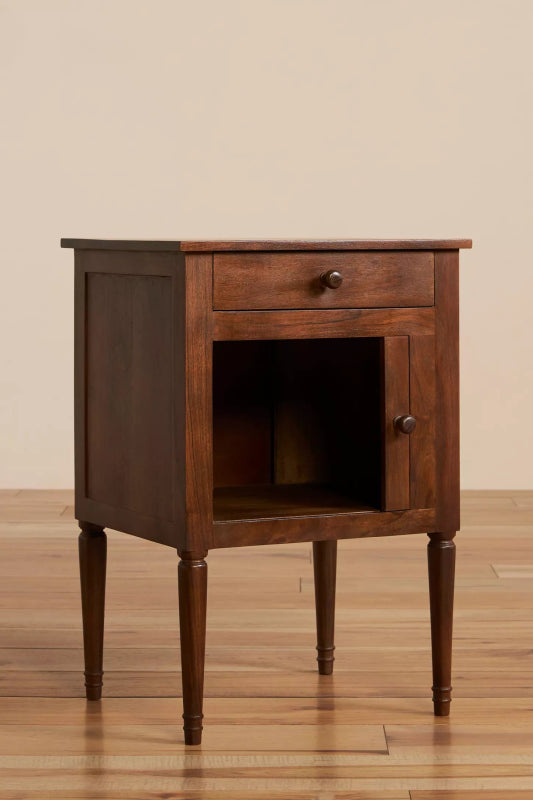 Natural finish mid-century bedside table with its cabinet door partially open, showing storage space beneath the drawer.