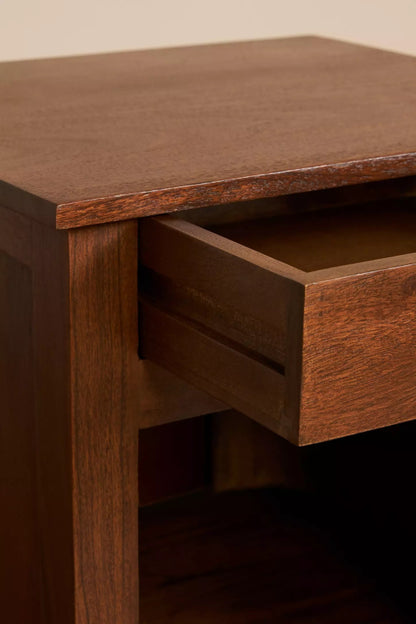 Close-up of a natural finish mid-century bedside table with its drawer open, showing the wooden interior and tabletop.