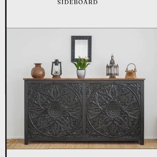 Black wooden mandala credenza video preview showing a front view of the carved floral doors, circular ring pulls and natural wood top, styled with decorative lanterns and pottery beneath a framed portrait.