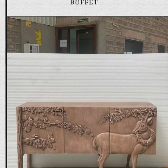 A hand-carved wooden land & sky buffet cabinet featuring an intricate, raised relief design of a detailed deer standing among pine branches and butterflies. The three-door storage unit stands on four elegant legs, showcasing natural wood grain textures with built-in interior shelving. It is presented both in a workshop setting and styled in a cozy room under a classic landscape painting.