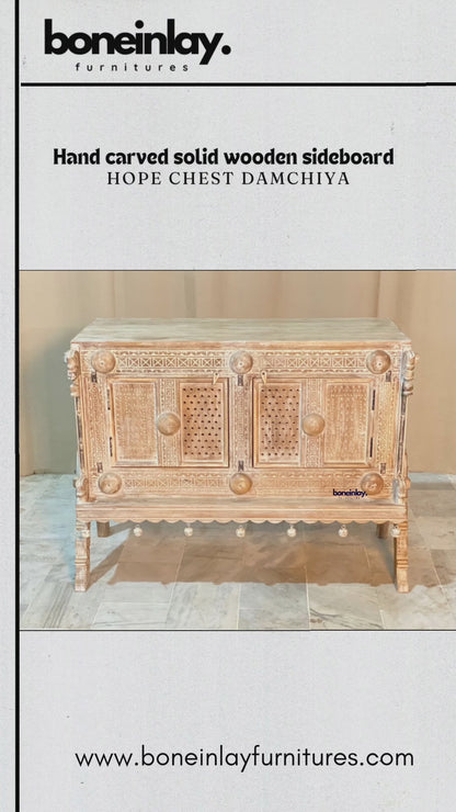 This video showcases a "Hand Carved Solid Wooden Sideboard Hope Chest Damchiya," a stunning piece of traditional Rajasthani furniture. The video highlights its intricate hand-carved geometric patterns, delicate perforated door panels, and distinctive hanging bell-style decorative accents along the base. The sideboard’s weathered finish and robust craftsmanship evoke a timeless, rustic charm, perfectly blending artisanal heritage with versatile home storage.