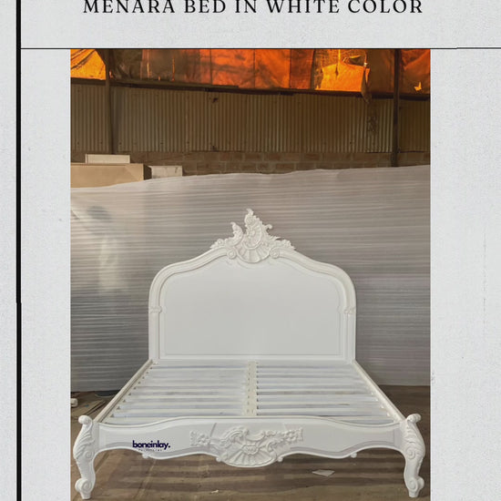 An advertisement video features a pristine white, handmade hand-carved wooden "Menara Bed" styled in elegant French Rococo design with an ornate shell-and-floral headboard, cabriole legs, and detailed relief carvings. The video pans smoothly across the empty platform frame inside a warehouse setting, showcasing its structural design and elaborate artisan craftsmanship up close. It concludes with a call-to-action screen displaying "Shop now," the website URL, and customer benefits like free worldwide deliver