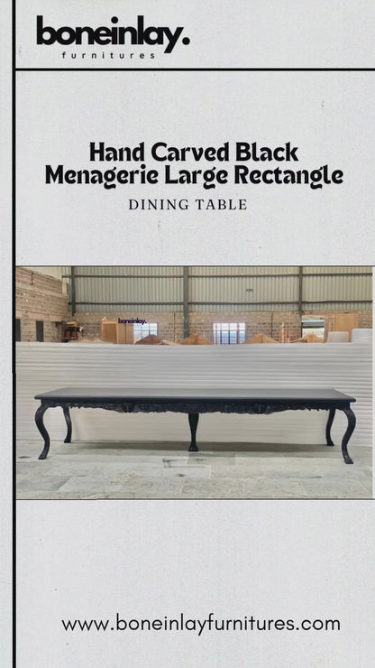 This video presents a grand, large rectangular dining table finished in a sophisticated matte black. The piece is a hallmark of artisan craftsmanship, characterized by its unique "menagerie" theme featuring hand-carved animal and floral motifs.