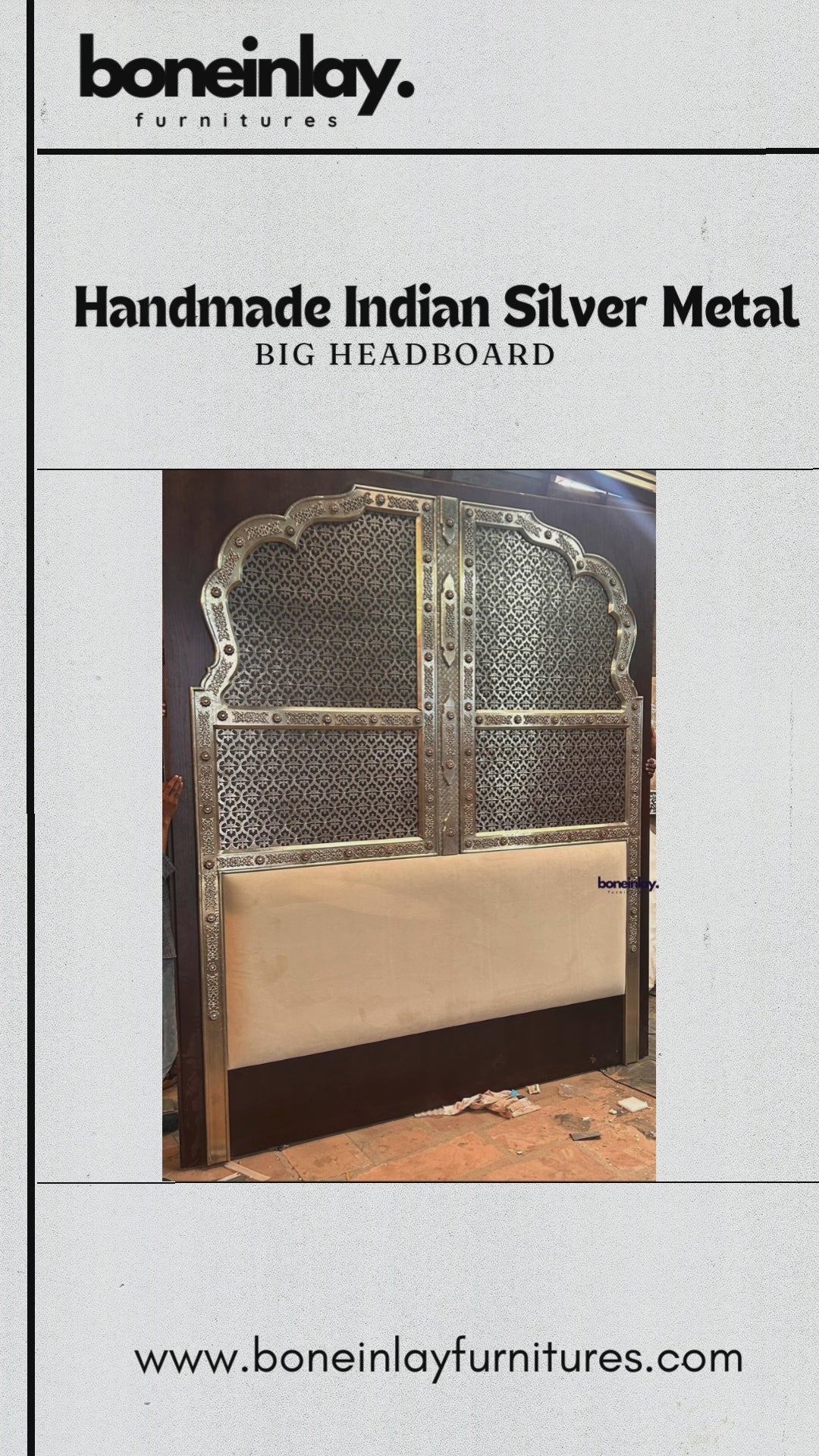 The "Handmade Indian Silver Metal Big Headboard" by boneinlay furnitures features an imposing, arched structure intricately decorated with traditional geometric openwork metal overlays. This elaborate silver pattern stands in contrast to the rich, dark wood frame, while the lower section is anchored by a smooth, cream-colored upholstered panel. The video showcases detailed close-ups of the fine metal embossing, demonstrating the craftsmanship from multiple angles.