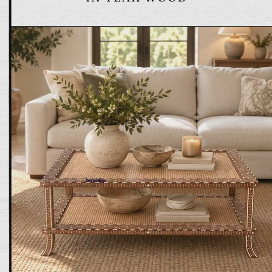 The video presents a handmade cane coffee table crafted in teak wood from Bone Inlay Furnitures. The rectangular two-tier table features woven cane panels on both shelves framed by intricate decorative inlay borders and curved legs. It is initially staged in a warm, cozy living room before being displayed on its own against a neutral background.