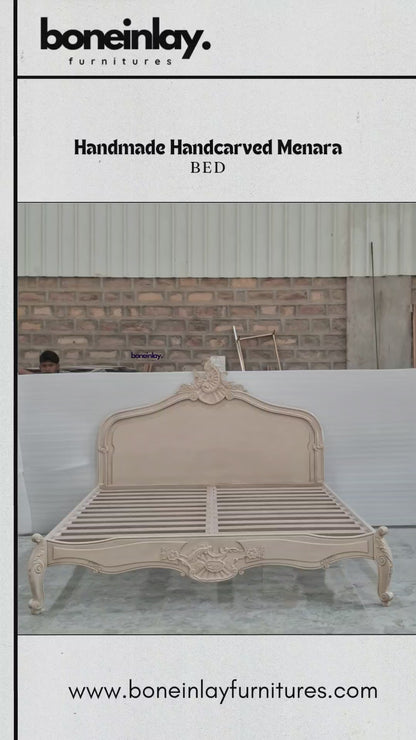 An advertisement video features a beige, handmade hand-carved wooden "Menara Bed" styled in elegant French Rococo design with an intricate shell-and-floral crest headboard, cabriole legs, and detailed relief carvings. The camera pans across the platform frame inside a spacious warehouse, highlighting the subtle color and artisan details from multiple sweeping angles. It concludes with a call-to-action screen displaying "Shop now," the website URL, and consumer incentives including free worldwide delivery an