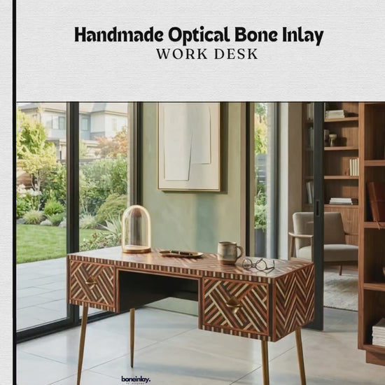An elegant, handmade work desk featuring an intricate "optical bone inlay" pattern. The desk showcases geometric striped patterns in shades of black, cream, and warm wood tones across its top and drawers. It features slender, tapered gold legs and two built-in drawers with circular gold handles.
