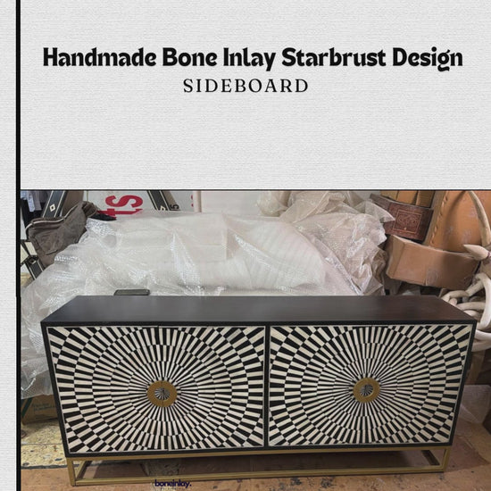 his "Handmade Bone Inlay Starburst Design Sideboard" features a striking, high-contrast geometric optical illusion pattern of radiating black and white tiles across its two cabinet doors. The center of each starburst is detailed with a large, decorative gold metallic circular ring handle that coordinates with the minimalist gold open frame base. The sideboard's clean-lined frame is finished in solid black, balancing its bold, graphic face with modern sophistication.