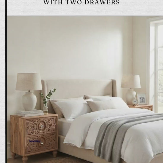 Hand-carved wooden nightstand with a natural matte finish styled in a modern bedroom.

Features two smooth storage drawers adorned with intricate floral motif carvings and clear crystal knobs.

Complements organic modern, bohemian, and transitional bedroom interiors with elegant artisan craftsmanship.