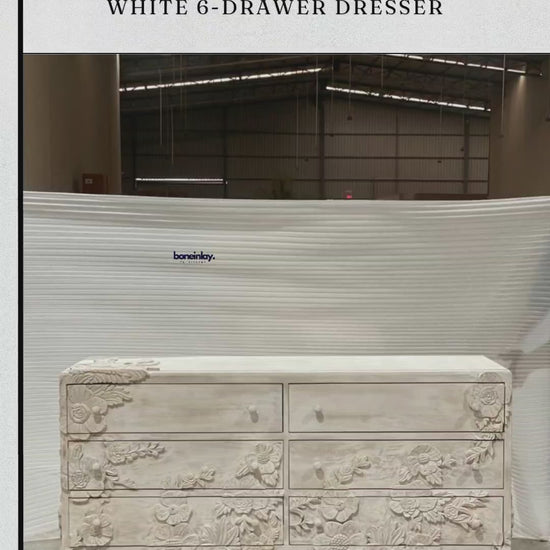 A wide, solid wood enchantment six drawers dresser in a distressed white finish, featuring six spacious drawers. The front of the piece is a masterpiece of craftsmanship, adorned with elaborate, 3D hand-carved floral sculptures that bloom across the drawer fronts and base.