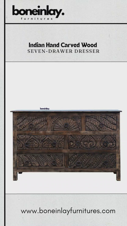 The dresser features a rich, dark wood finish with intricate hand-carved floral and fan-like motifs across all seven drawers.
A hand is shown opening one of the top drawers to demonstrate the smooth functionality and solid wood interior. 