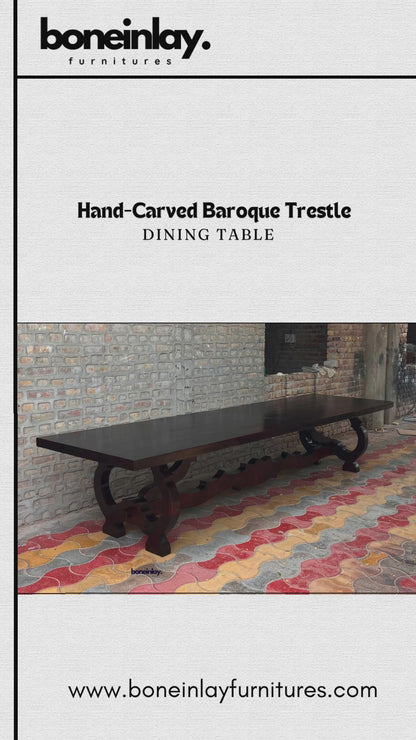 A promotional video showcases a Hand-Carved Baroque Trestle Dining Table, featuring a dark-stained wood finish and an intricately designed base. The clip frames the elongated table from multiple angles in an outdoor space before transitioning to a staged dining room setting, where it is surrounded by elegant chairs under a chandelier.