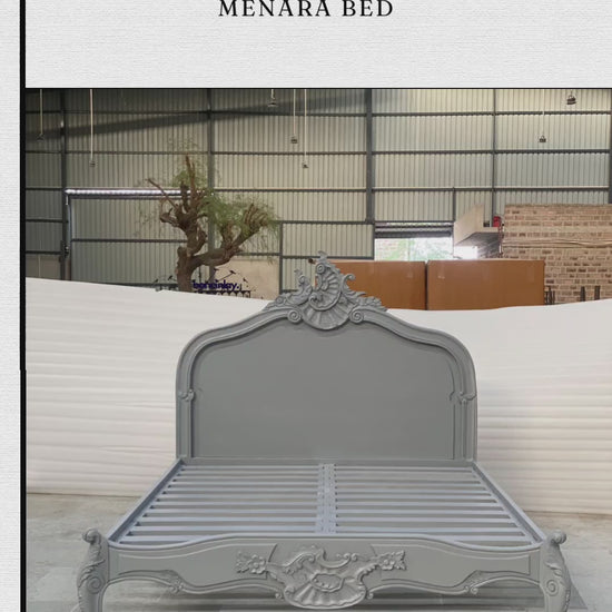 An advertisement video features a light gray, hand-carved solid wooden "Menara Bed" styled in classic French Rococo design with an ornate headboard, cabriole legs, and elaborate floral motifs. The video showcases the bed frame from various sweeping angles inside a manufacturing warehouse, transitioning to a collage of detailed close-ups highlighting the intricate craftsmanship. It concludes with a call-to-action screen displaying "Shop now," the website URL, and promotional benefits like free worldwide deli
