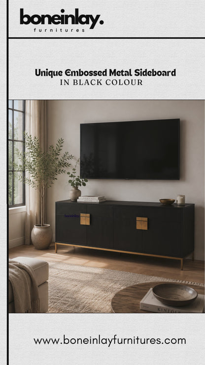 Modern black embossed metal sideboard buffet cabinet featuring sleek textured doors and square gold hardware. Designed as a stylish credenza and accent storage cabinet, this low-profile piece is displayed in a contemporary living room setting beneath a flat-screen TV, offering modern elegance and functional storage with premium brass-toned handles and slim metal legs.