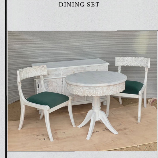 This video showcases a "Handcarved Handmade Fable Dining Set," featuring a round pedestal table, matching chairs with teal upholstered seats, and a coordinating sideboard. The entire set is finished in a distressed white, highlighting the intricate hand-carved floral and architectural details across the table's apron, the chair backrests, and the sideboard doors. Close-ups emphasize the artisanal craftsmanship and the elegant, traditional aesthetic of the collection.