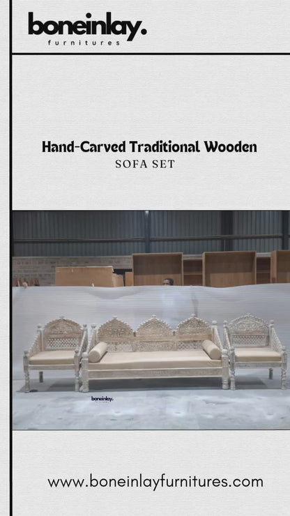 A showcase of the Hand-Carved Maharaja Triple Arch Sofa Set in a stunning distressed white-wash finish. This artisanal collection features a grand three-seater sofa and two matching armchairs, all meticulously hand-carved from premium solid wood. The design is defined by its majestic triple-arched backrests, intricate floral lattice (jali) work, and high-relief botanical carvings. Each piece includes plush, neutral-toned seat cushions and stands on masterfully turned legs with sculptural accents. The video 