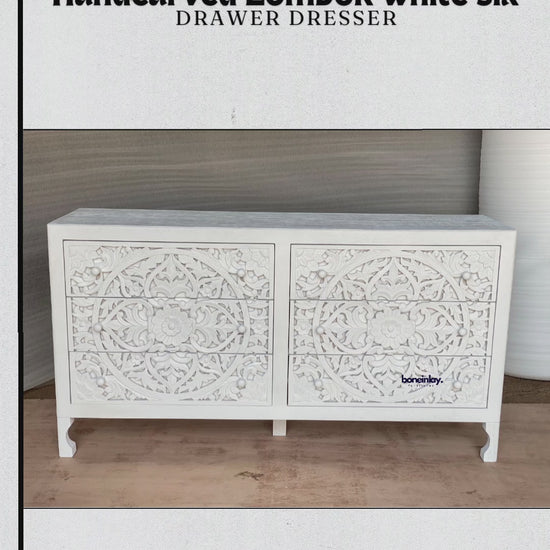 A wide, white-finished wooden dresser featuring six drawers entirely covered in intricate, hand-carved floral and vine motifs. The piece blends traditional craftsmanship with a clean, bohemian aesthetic, supported by four tapered legs. The video highlights the deep texture of the carvings and the smooth, matte surface of the dresser's top.