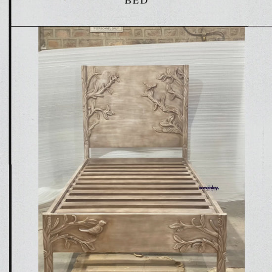 This video showcases a twin-size bed frame meticulously hand-carved with a detailed "Ornithology" theme, featuring birds perched among graceful tree branches on both the headboard and footboard. The solid wood frame has a soft, weathered finish that highlights the depth of the artisanal carvings and the organic wood grain. The camera pans across the sturdy slatted base and provides close-up views of the intricate wildlife motifs, emphasizing the blend of nature-inspired art and functional furniture design.